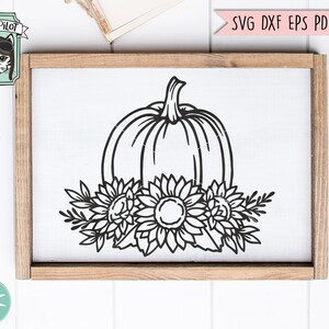 May include: Black and white line art design of a pumpkin with sunflowers around it. The design is on a white background and is framed in a wooden frame.