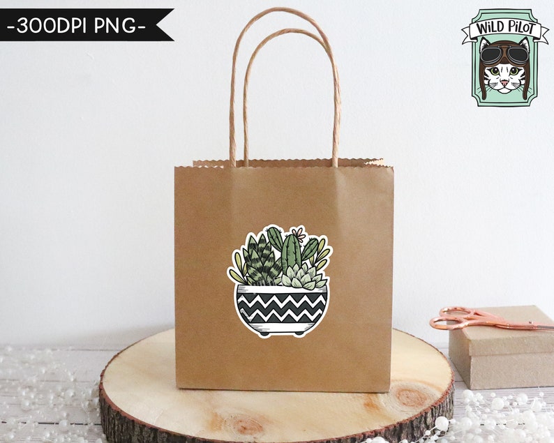 May include: A brown paper gift bag with a sticker of a potted succulent plant. The sticker has a black and white chevron pattern on the pot. The bag has a white handle. The text "Wild Pilot" is in a green banner with a cat wearing aviator goggles.