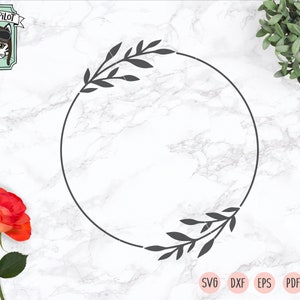 May include: A black and white circular frame with leafy branches on either side. The frame is on a white marble background.