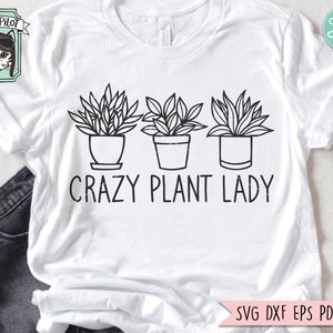 Könnte beinhalten: Weißes T-Shirt mit einer schwarzen Linienzeichnung von drei Topfpflanzen und dem Text "Crazy Plant Lady".