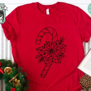 May include: A red t-shirt featuring a black outline of a candy cane and a poinsettia flower.