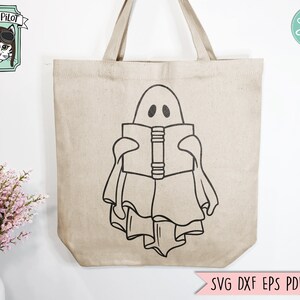 May include: A white tote bag with a black outline of a ghost reading a book. The ghost has two eyes and a mouth. The tote bag has a brown handle.