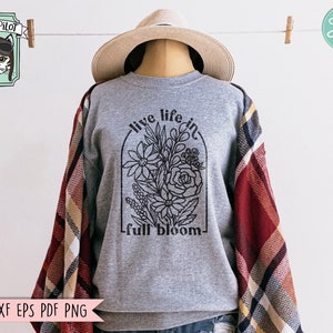 Pode incluir: Uma camisa de moletom cinza com um desenho floral preto e o texto "live life in full bloom".