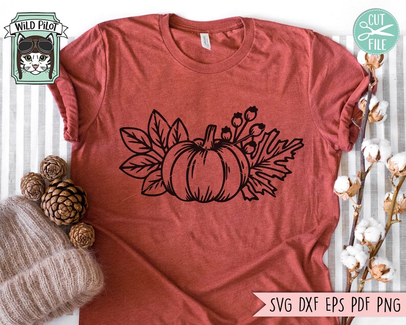 May include: A black and white line drawing of a pumpkin with leaves and berries. The image is on a red t-shirt.