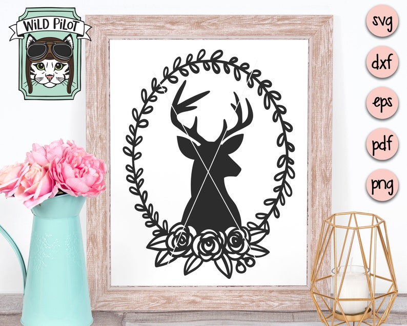 K&ouml;nnte beinhalten: Schwarze Silhouette eines Hirschkopfes mit Geweih in einem Kranz aus Bl&auml;ttern mit Rosen am Boden. Das Design ist auf wei&szlig;em Hintergrund.
