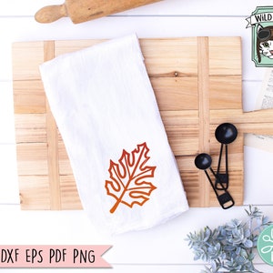 May include: A white kitchen towel with a red-orange maple leaf design. The towel is on a wooden cutting board with two black measuring spoons. The text "SVG DXF EPS PDF PNG" is at the bottom of the image.
