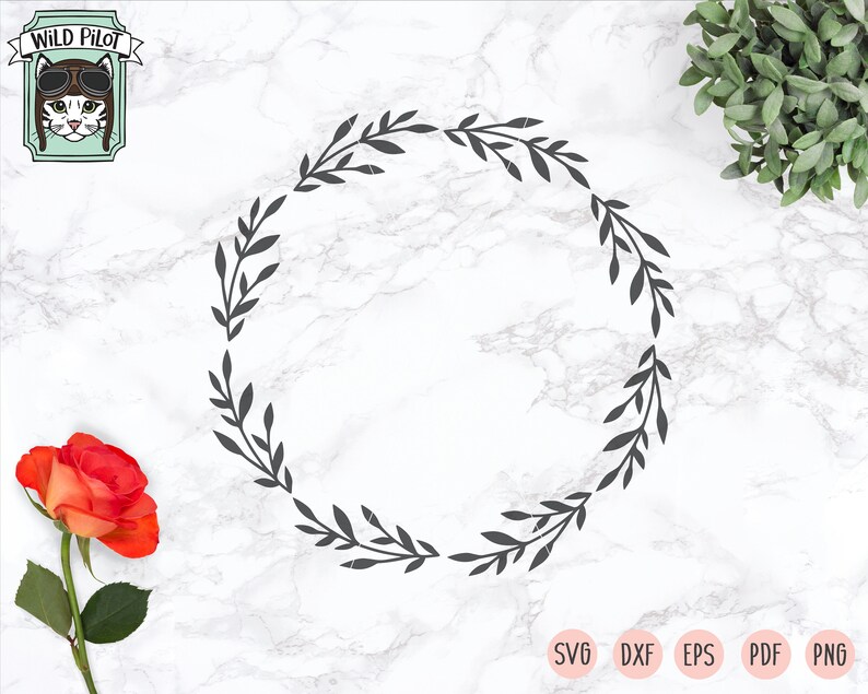 May include: A black and white wreath with a simple leaf design. The wreath is on a white marble background.