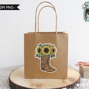 May include: A brown paper gift bag with a sticker of a pair of cowboy boots with sunflowers on top. The sticker says "Wild Pilot" with a cartoon cat wearing aviator sunglasses.