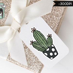 May include: A white gift tag with a black and white polka dot pot with a green cactus plant with pink flowers. The tag is on top of a gold glitter gift box with a white ribbon.
