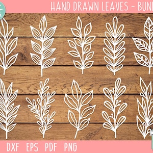 Op de afbeelding: Een set van tien handgetekende bladillustraties in wit, perfect voor knutselprojecten. De bladeren zijn gerangschikt in twee rijen van vijf op een houtnerf achtergrond. De tekst "HAND DRAWN LEAVES - BUNDLE 2" staat bovenaan de afbeelding.