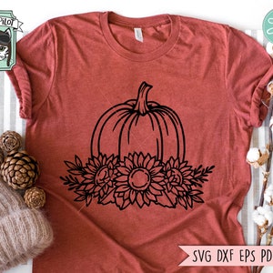 May include: A black and white line drawing of a pumpkin with sunflowers around it. The pumpkin is centered and the sunflowers are arranged around the bottom of the pumpkin.