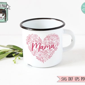 Pu&ograve; includere: Una tazza di smalto bianco con bordo e manico neri. La tazza presenta un design a forma di cuore floreale rosa con la parola "Mama" al centro.