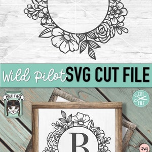 May include: Black and white floral wreath with a circle in the center for a monogram. The letter "B" is in the circle. The wreath is on a white background with a wood grain texture.