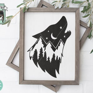 May include: Black and white silhouette of a wolf howling at the moon with a mountain range and trees inside the silhouette. The image is on a white background with a wooden frame.