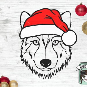 May include: Black and white line art illustration of a wolf's face wearing a red Santa hat. The wolf is looking directly at the viewer. The image is set against a white woodgrain background.