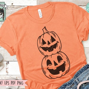 May include: Orange t-shirt with a black graphic of two stacked jack-o'-lantern pumpkins with smiling faces.