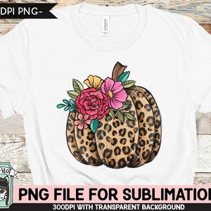 May include: A white t-shirt with a sublimation design of a leopard print pumpkin with pink, orange, and yellow flowers.