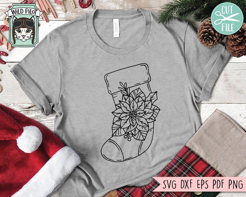 May include: A black and white line drawing of a Christmas stocking with a poinsettia flower on a grey t-shirt. The text "SVG DXF EPS PDF PNG" is at the bottom of the image.