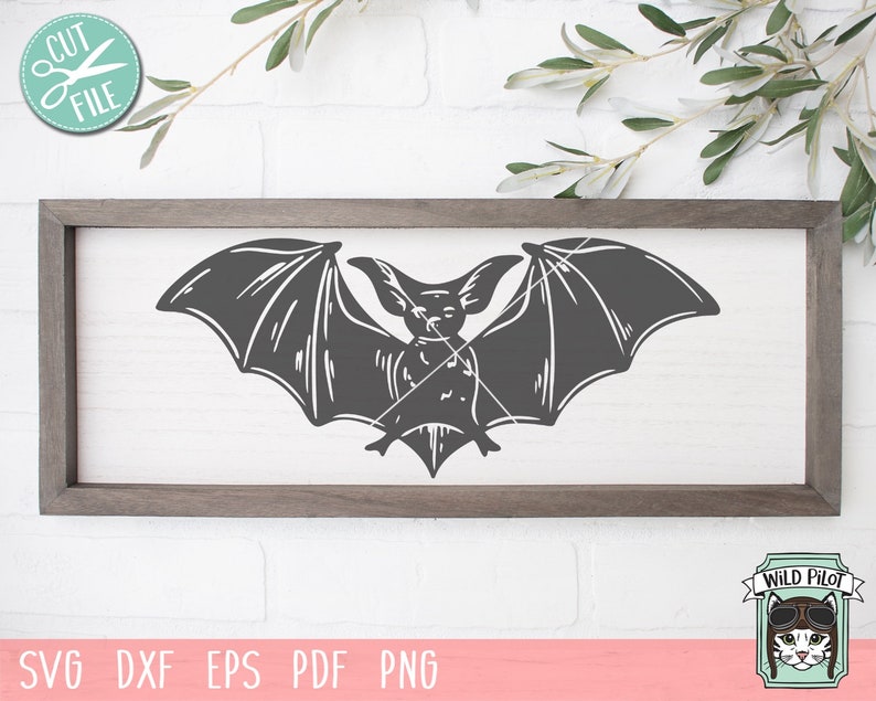 May include: A black silhouette of a bat with its wings spread wide. The bat is centred on a light grey background within a wooden frame.