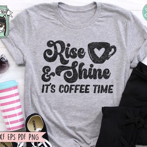 May include: A gray t-shirt with a black graphic that says "Rise & Shine It's Coffee Time". The graphic includes a stylized coffee cup with a heart.