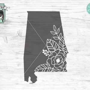 May include: A gray outline of the state of Alabama with white floral designs on the right side. The floral design includes leaves, vines, and a large flower.