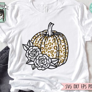 May include: A black and gold pumpkin with a leopard print design and white flowers. The pumpkin is outlined in black and has a stem.