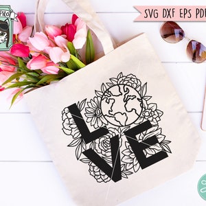 May include: A white tote bag with a black and white design of the word "LOVE" with a floral pattern and a globe in the center. The design is on a white canvas tote bag.