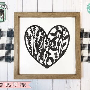 May include: A black silhouette of a heart filled with floral designs. The heart is centered on a white background inside a brown wooden frame.