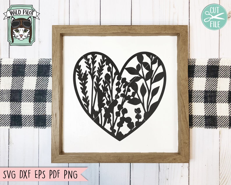 May include: A black silhouette of a heart filled with floral designs. The heart is centered on a white background inside a brown wooden frame.