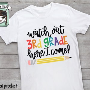 Peut inclure: Un t-shirt blanc avec le texte "watch out 3rd GRADE here I come!" en couleurs arc-en-ciel. Un crayon jaune avec une gomme rouge est dessin&eacute; sous le texte.