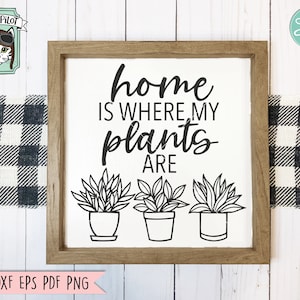 May include: A wooden sign with the text "home is where my plants are" in black lettering. Three potted plants are illustrated below the text.