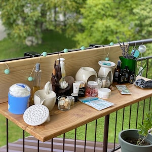 May include: A wooden shelf with a variety of items, including candles, essential oils, and other spa-related products. The shelf is decorated with a string of lights and a small plant.