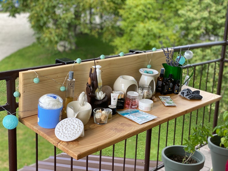 May include: A wooden shelf with a variety of items, including candles, essential oils, and other spa-related products. The shelf is decorated with a string of lights and a small plant.