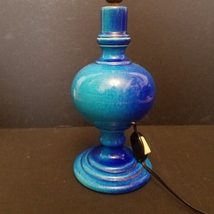 May include: A blue ceramic table lamp with a round base and a blue and green gradient. The lamp has a cord with an inline switch.