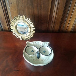 May include: A white ceramic owl-shaped dish with black eyes and a black beak. The dish has three compartments, each with a black rim.