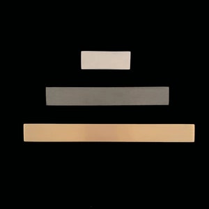 Op de afbeelding: Drie horizontale strepen in een piramidevorm. De bovenste streep is wit, de middelste streep is grijs en de onderste streep is lichtbruin.