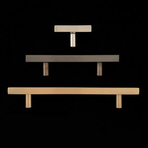 Peut inclure: Trois poign&eacute;es de porte de diff&eacute;rentes tailles et finitions. La poign&eacute;e du haut est une petite poign&eacute;e en T argent&eacute;e. La poign&eacute;e du milieu est une poign&eacute;e rectangulaire plus grande avec une finition nickel bross&eacute;. La poign&eacute;e du bas est la plus grande, une poign&eacute;e rectangulaire avec une finition or bross&eacute;.