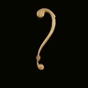 Może przedstawiać: Złoty metalowy klamka do drzwi z ozdobnym wzorem. Klamka ma kształt znaku zapytania i posiada wzór kwiatowy.