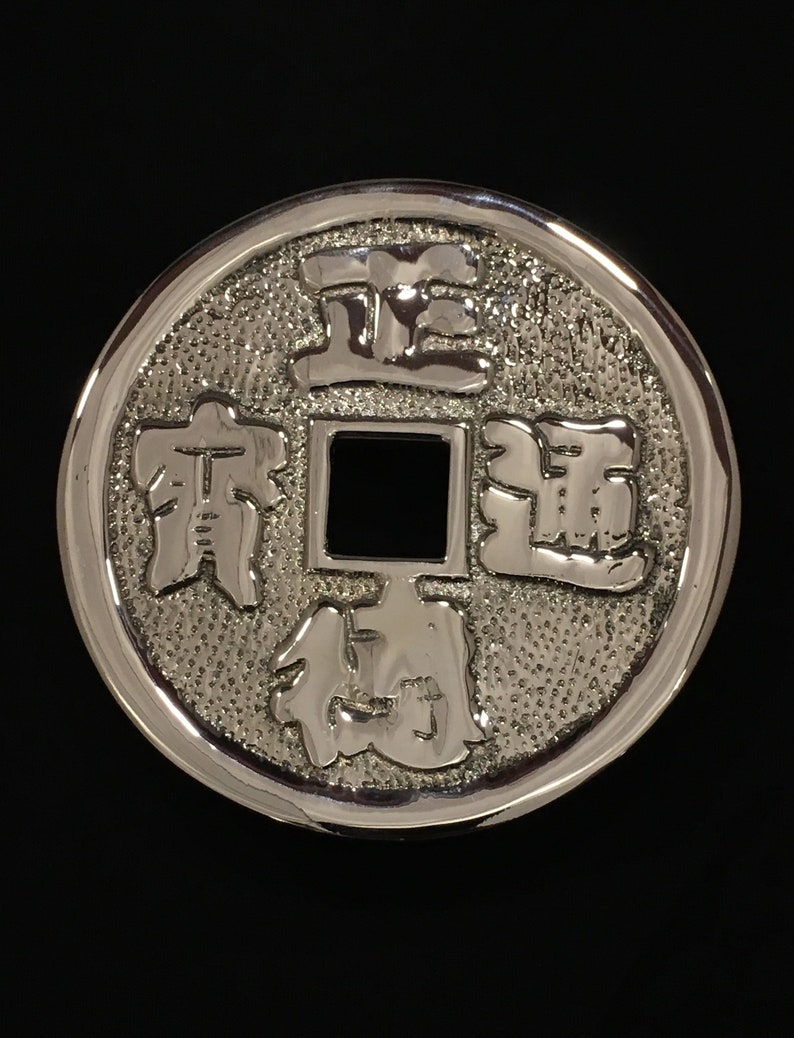 Puede incluir: Una moneda china de plata con letras en relieve y un agujero cuadrado en el centro. La moneda presenta los caracteres chinos "正" (Zheng), "通" (Tong), "寶" (Bao) y "錢" (Qian).