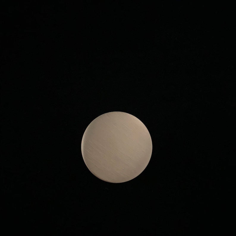 May include: A close-up of a round, white, textured disc against a black background.