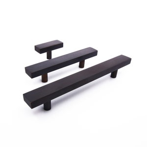 Peut inclure: Trois poign&eacute;es de tiroir en m&eacute;tal noir de diff&eacute;rentes tailles. Les poign&eacute;es ont une forme rectangulaire aux bords arrondis.