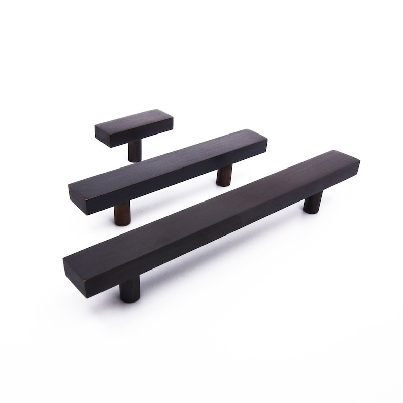 Peut inclure: Trois poign&eacute;es de tiroir en m&eacute;tal noir de diff&eacute;rentes tailles. Les poign&eacute;es ont une forme rectangulaire aux bords arrondis.