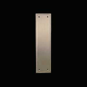 Puede incluir: Un tirador de puerta de níquel cepillado con un borde de diseño de cuerda. El tirador tiene dos agujeros para montaje.