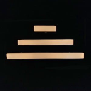 Peut inclure: Trois poignées de tiroir rectangulaires beiges de différentes tailles.