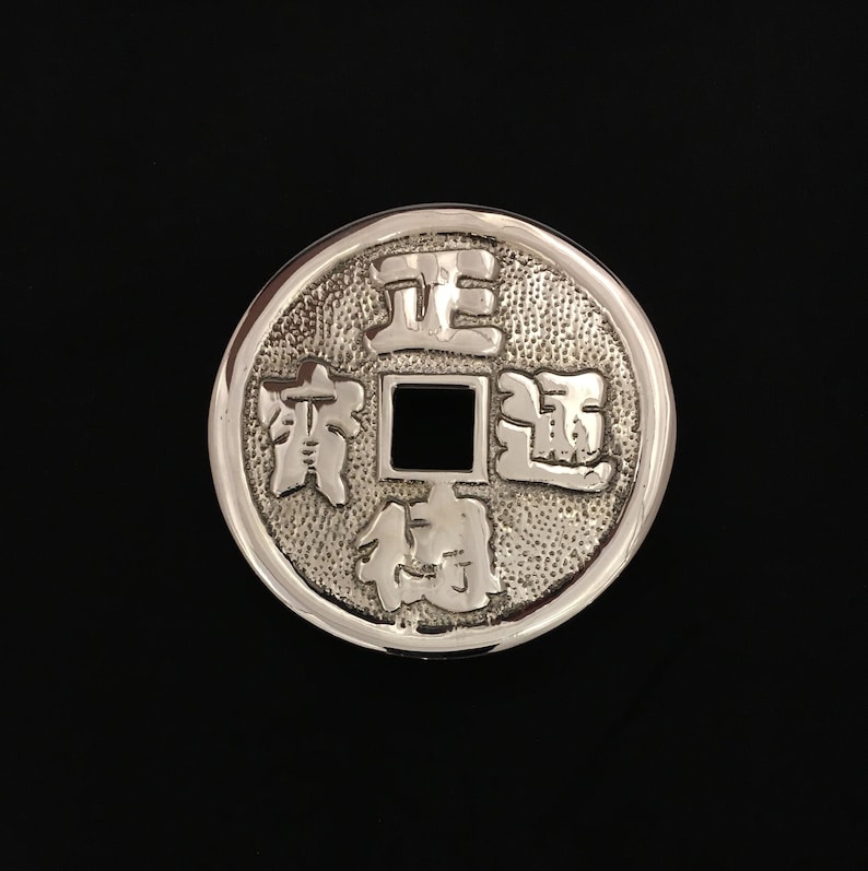 Puede incluir: Una moneda china de plata con los caracteres "Zheng Da Guang" y un agujero cuadrado en el centro.