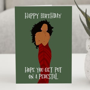 May include: A green card with the text "Happy Birthday" and "Hope you get put on a pedestal". The card features a digital illustration of a woman with dark curly hair wearing a red dress.