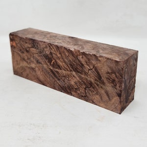 Könnte beinhalten: Ein dunkelbrauner Holzrohling mit einem einzigartigen Maserungsmuster. Das Holz ist glatt und poliert und bereit, zu einem wunderschönen Kunstwerk verarbeitet zu werden.