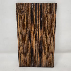 May include: Two pieces of wood with a dark brown and black striped pattern. The wood is approximately 4 inches wide and 6 inches long.