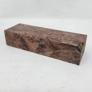 Könnte beinhalten: Ein rechteckiger Holzblock mit einem braunen und violetten Maserungsmuster. Das Holz hat eine natürliche, unbehandelte Optik.