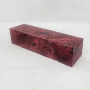 Könnte beinhalten: Ein rechteckiger Block aus rotem Holz mit einem wirbelnden Maserungsmuster.